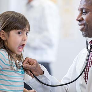 A little girl is surprised by the cold touch of the doctor's stethoscope.